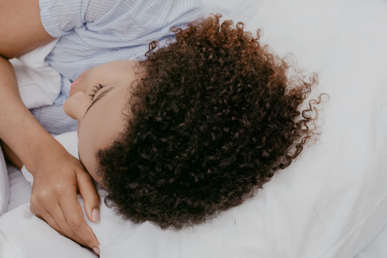 Side sleeper resting on a mattress that allows shoulders and hips to sink for spinal alignment